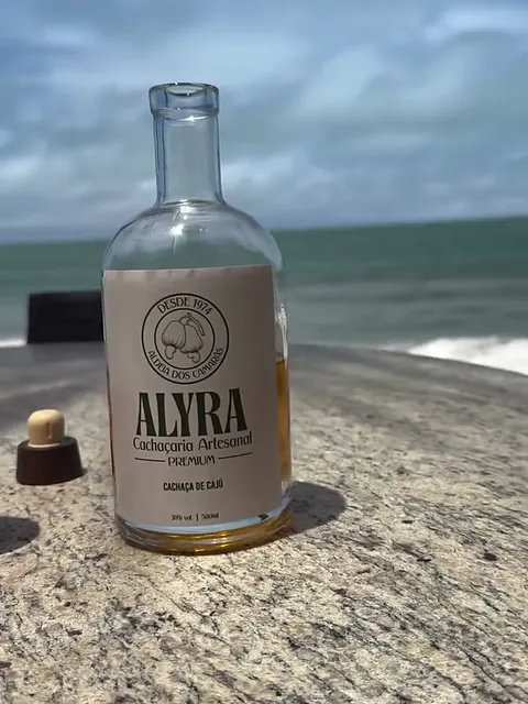 Garrafa redonda de 750 ml da ALYRA numa mesa de granito, com o mar ao fundo