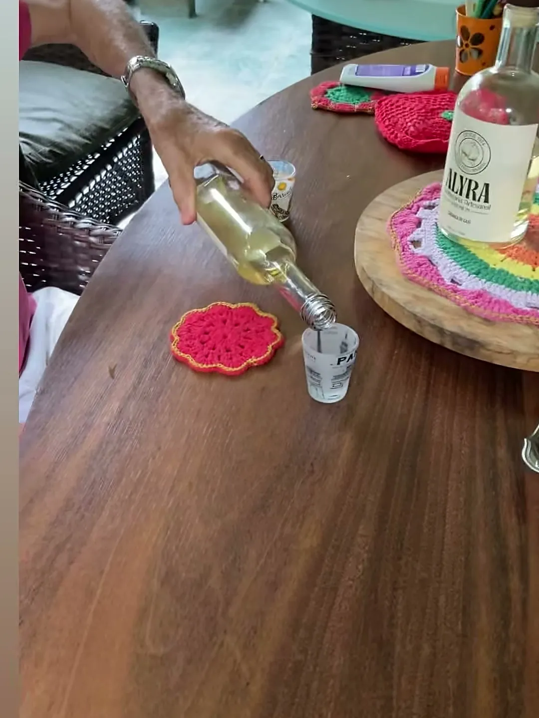 Dose de ALYRA sendo servida no copinho, na mesa da varanda